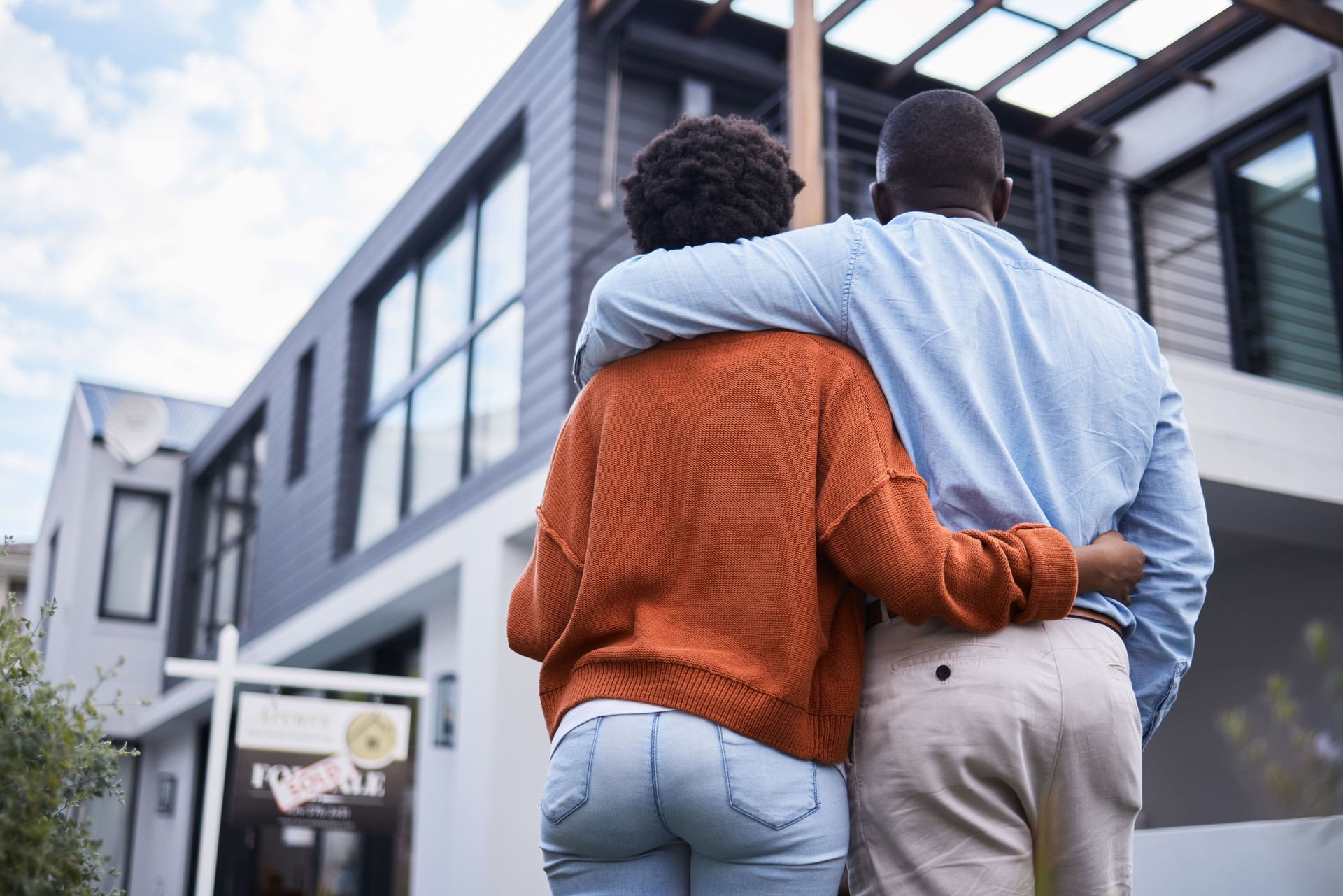 Rückansicht eines jungen Paares, das vor seinem neuen Zuhause steht